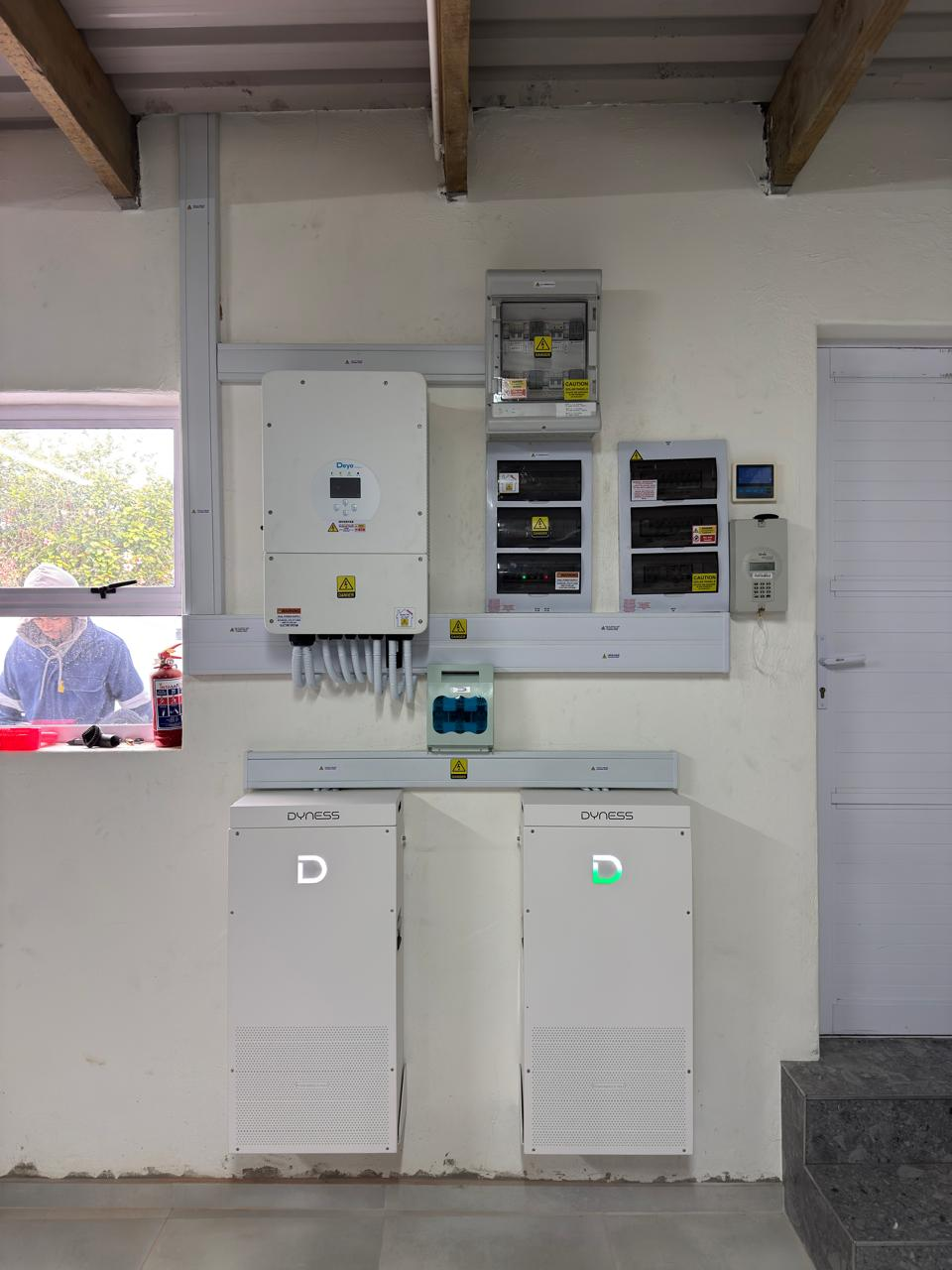 Wall-mounted Deye inverter, two Dyness batteries and labelled electrical distribution boards