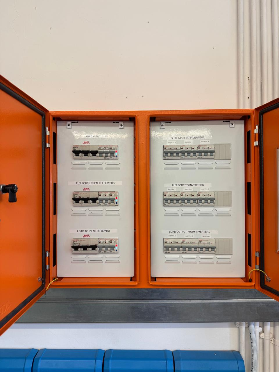 Two open orange electrical cabinets with labelled circuit breakers for inverter inputs and outputs