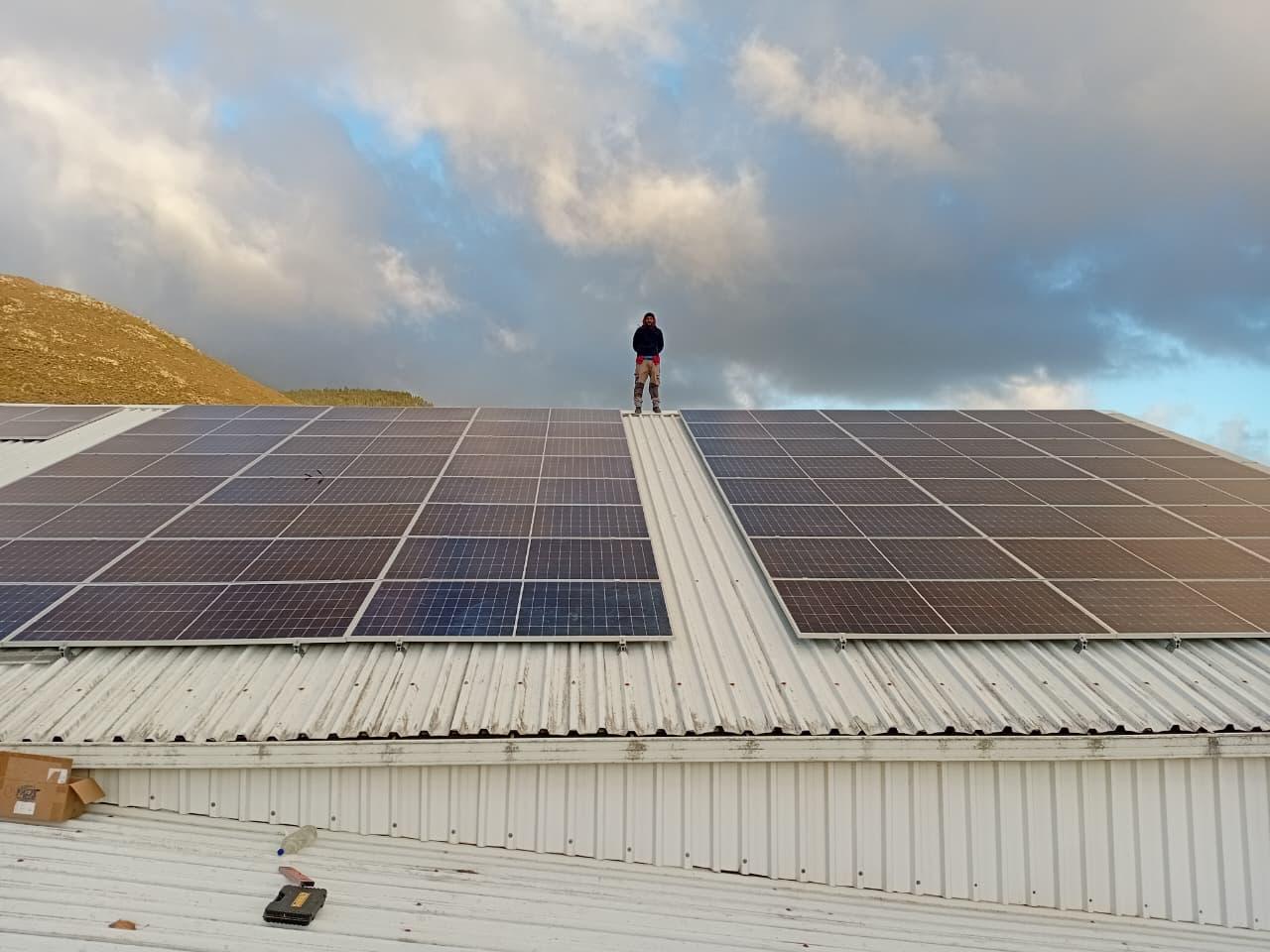 A team member beside a large roof-mounted solar array