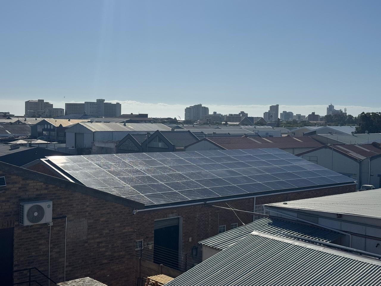 Solar panels on a brick commercial building with a city skyline behind