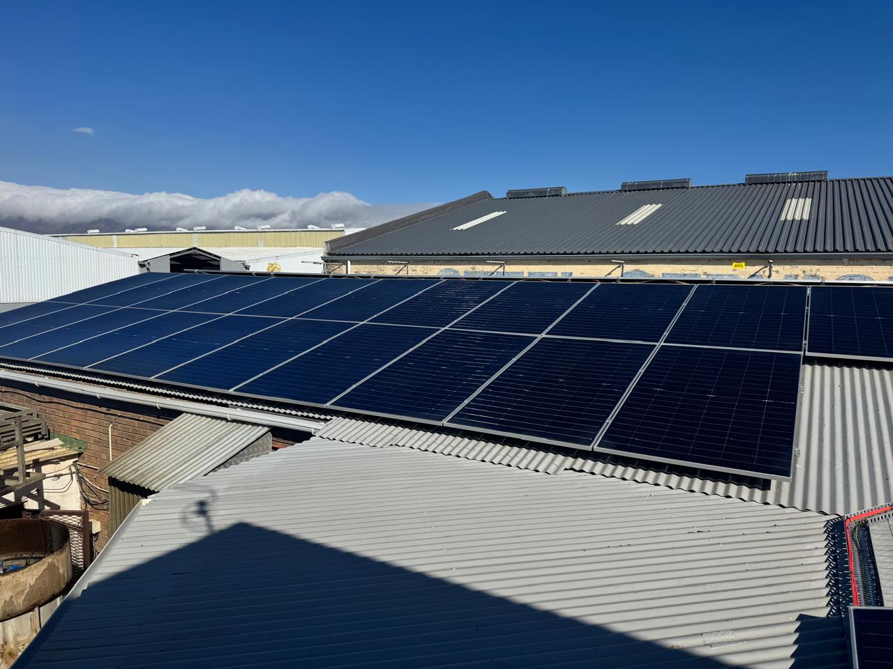 Front view of a large solar panel array on a commercial metal roof
